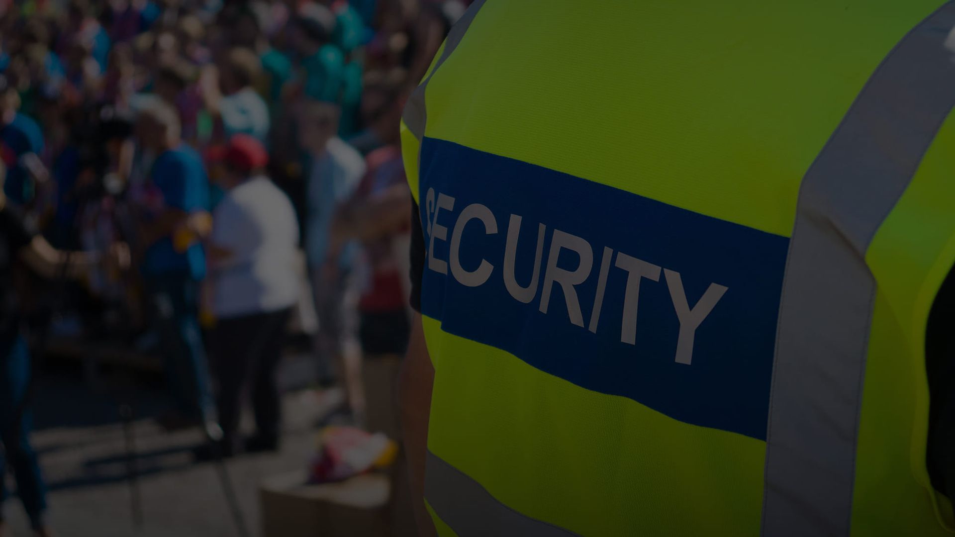 Fokussierter Blick auf die Weste eines Sicherheitspersonals mit der Aufschrift SECURITY vor einer überfüllten Veranstaltung im Freien